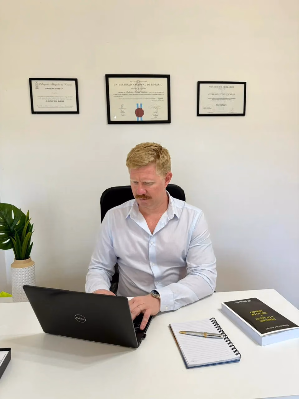 Federico Zalazar trabajando en su oficina, con sus diplomas de la UNR y del Colegio de Abogados de Rosario